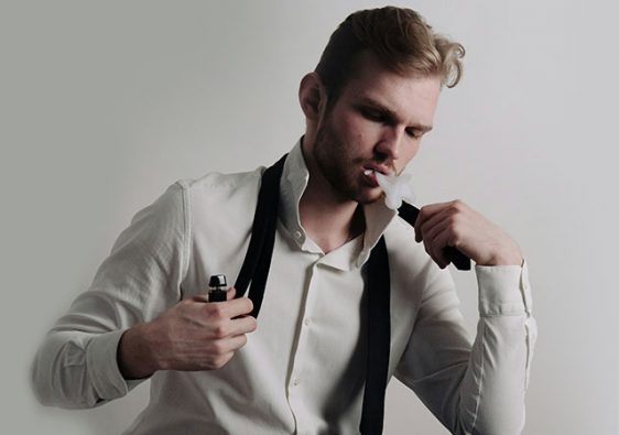 a man wearing a white dress shirt with black tie holding a vape in his hand while vaping